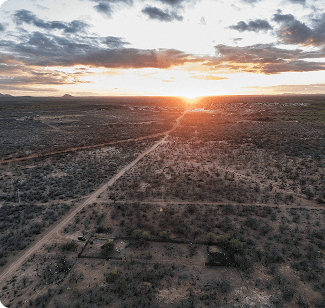 Aerial view of a vast desert landscape during sunset, showcasing dry terrain and sparse vegetation.